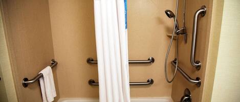 Un baño con bañera, barras de apoyo y cabezal de ducha.