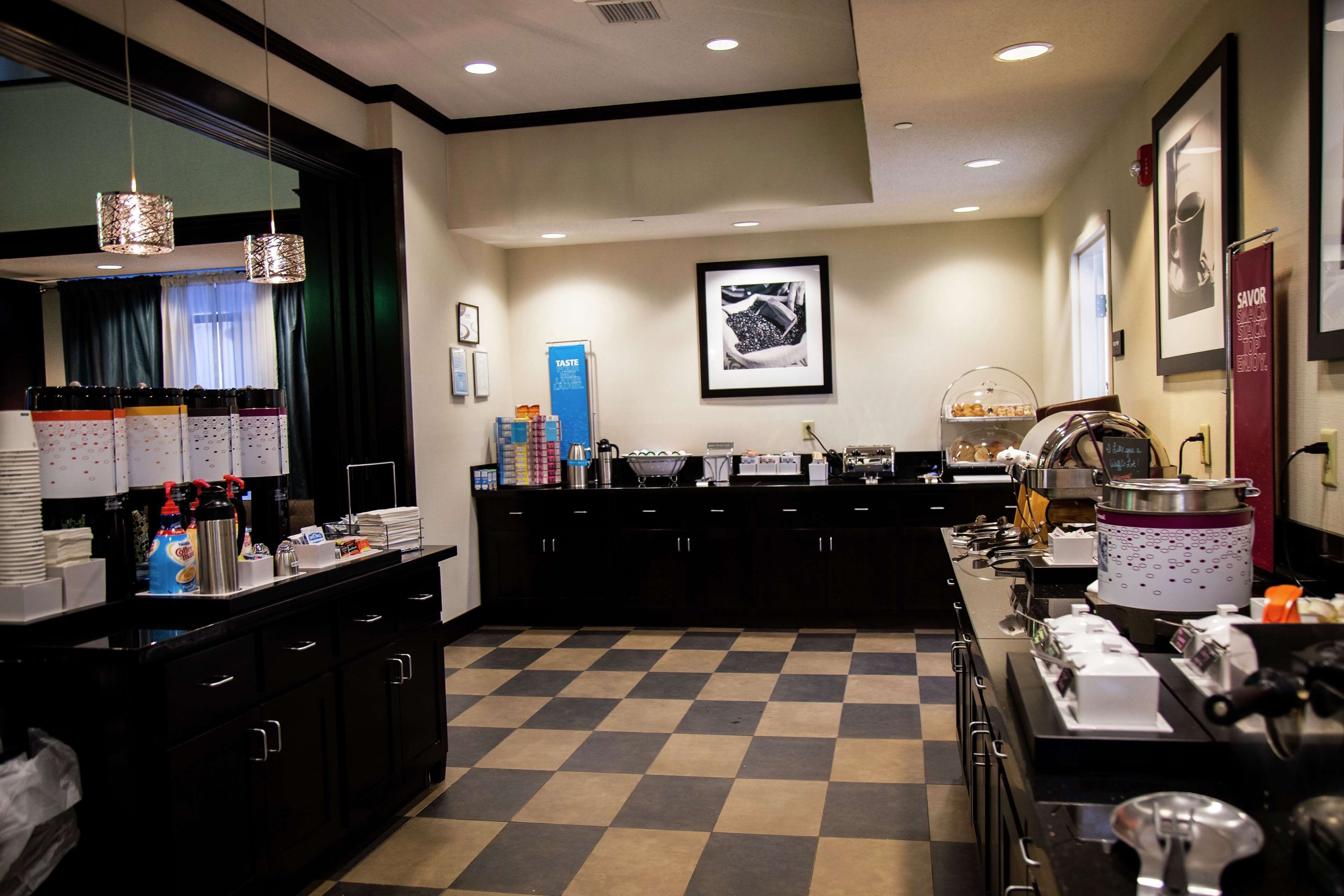 A hotel kitchen with a checkered floor, a coffee station, and a buffet area.