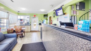 Zona de recepción con mostrador, sillas, sofá y una puerta señalizada con 