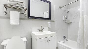 A modern bathroom with a toilet, sink, mirror, towel rack, and shower.