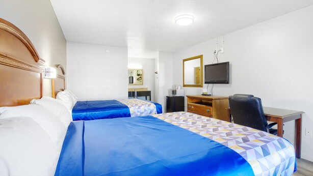 Habitación de hotel con dos camas, un escritorio, una silla, un televisor y un espejo.