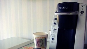 A Keurig coffee maker with a cup of coffee and several coffee pods on a tray. - The Milestone Inn (Woodbury)