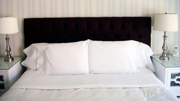 A hotel room with a large bed, two bedside tables with lamps, and a striped wall. - The Milestone Inn (Woodbury)