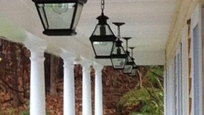 A covered porch with white columns and black hanging lanterns. - The Milestone Inn (Woodbury)