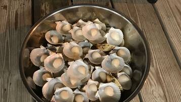 A metal bowl filled with scallops on a wooden deck.