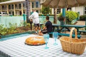 A checkered table with a sandwich, two glasses, and a basket.
