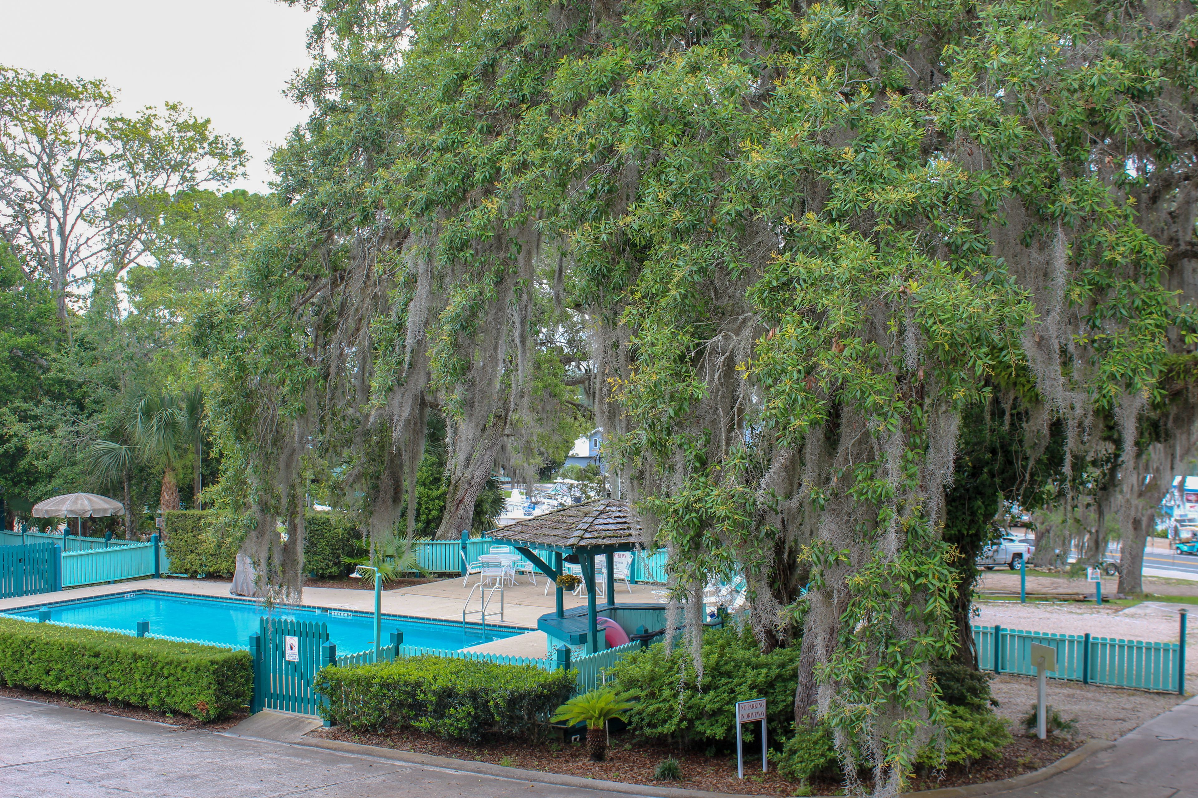 A pool area with a gazebo, surrounded by trees and a fenced pool.