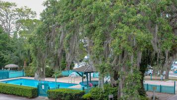 A pool area with a gazebo, surrounded by trees and a fenced pool.
