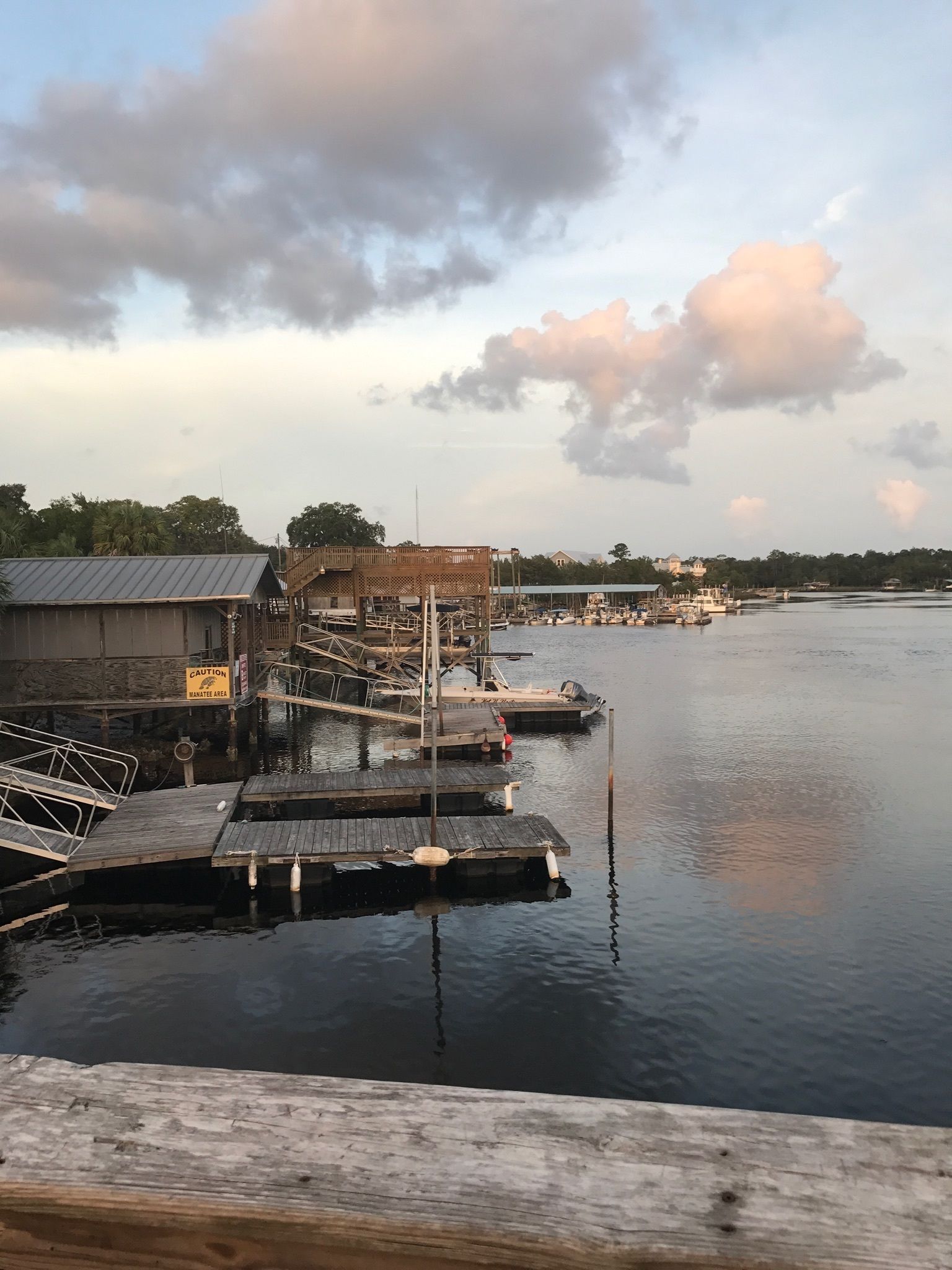 A waterfront dock with wooden platforms and a caution sign.