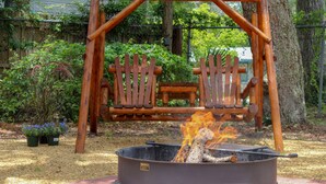 A wooden swing set with a fire pit in the center.