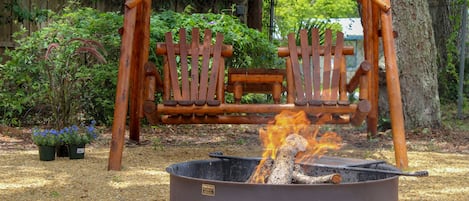 A wooden swing set with a fire pit in the center.