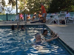 A swimming pool with people in the water and on the deck.