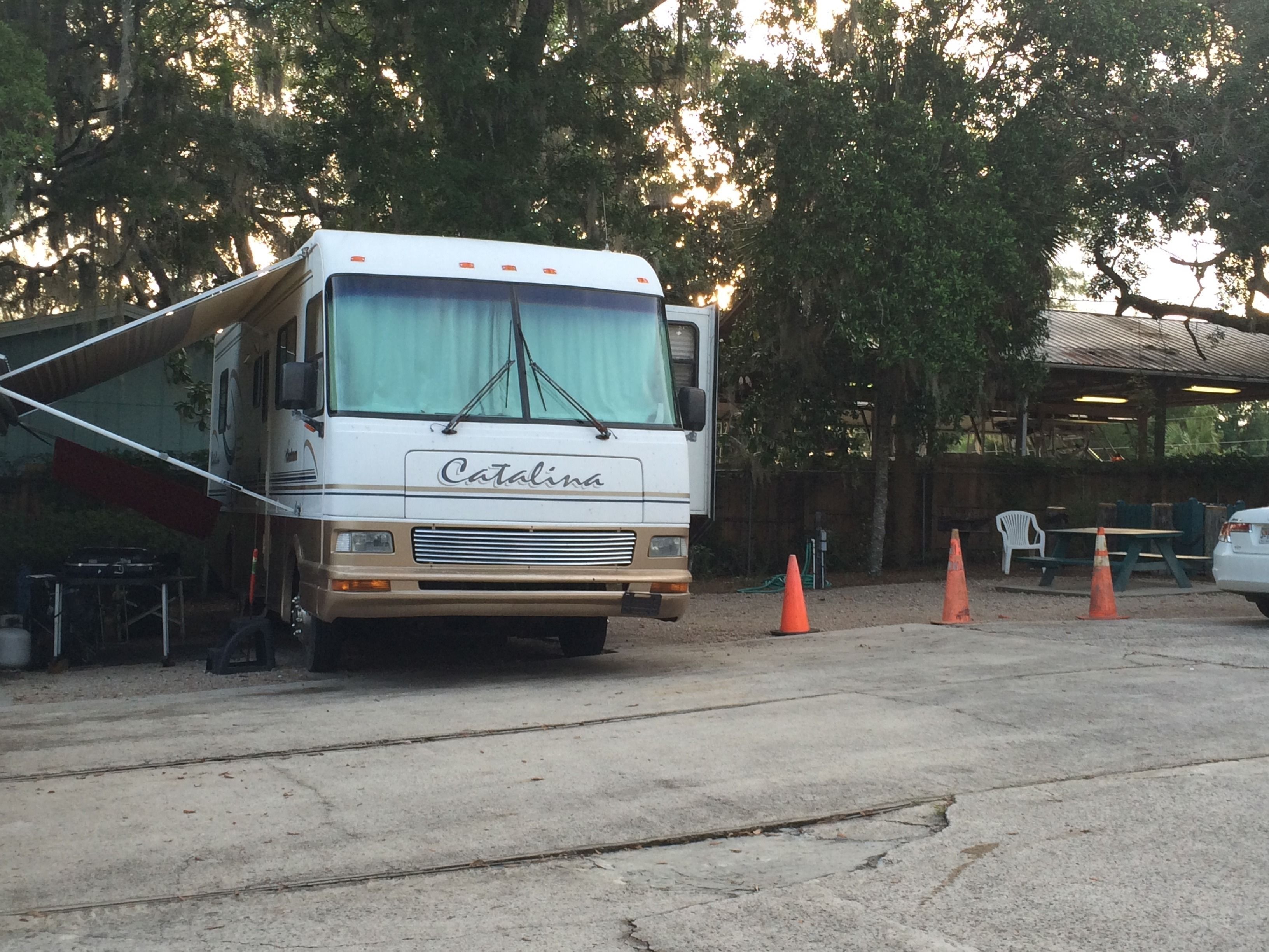 A Catalina RV parked in a parking lot with trees in the background.