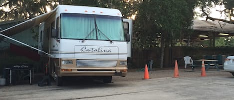 A Catalina RV parked in a parking lot with trees in the background.