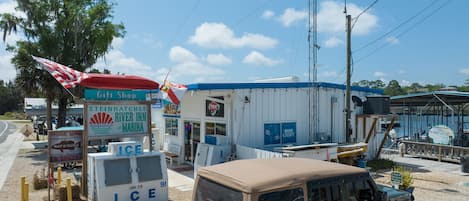 A small roadside establishment with a sign for a gift shop, a river inn, and a marina. A vehicle is parked nearby.