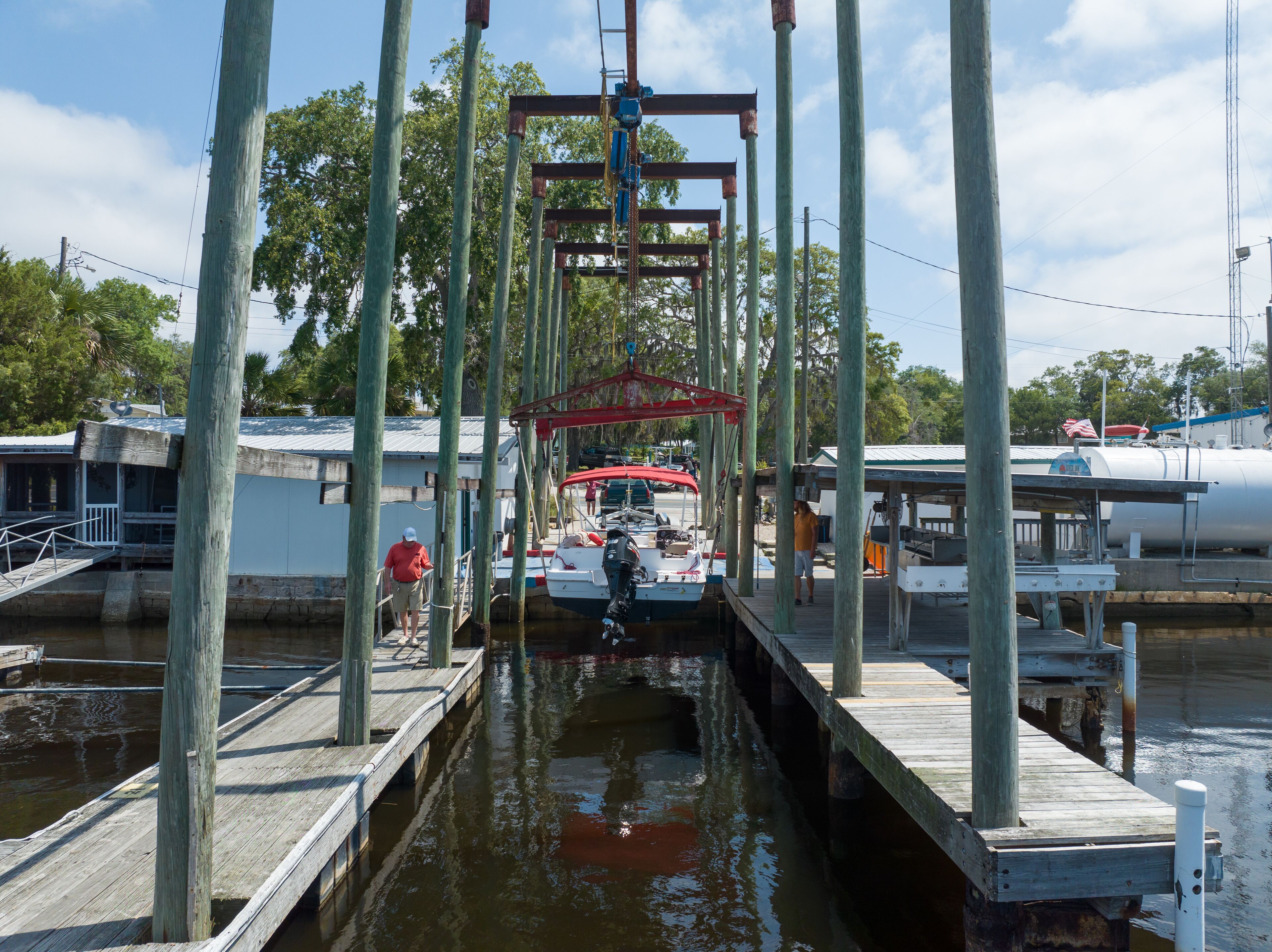 A dock with a boat, wooden pilings, and a small building.