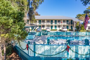 A hotel with a swimming pool, outdoor seating, and a covered area.