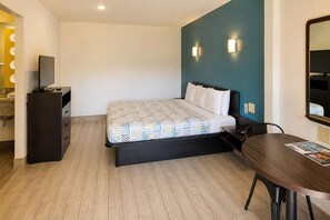 A hotel room with a bed, a desk, a chair, a television, and a bathroom visible in the background. - Studio 6 San Antonio, TX - Lackland AFB (San Antonio)