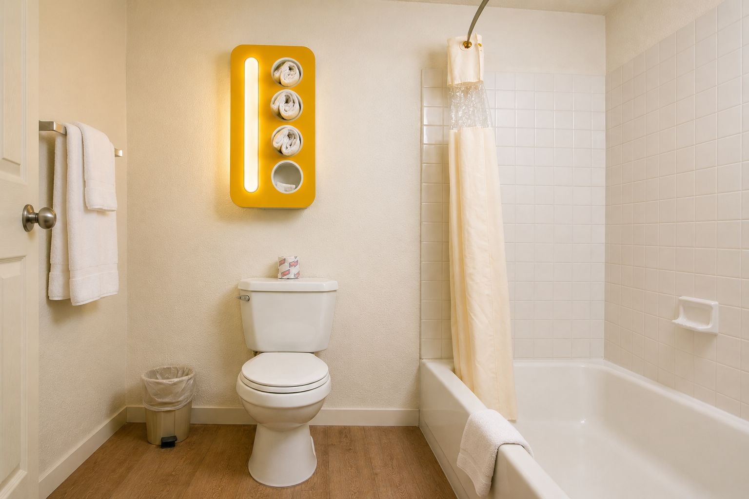 A bathroom with a toilet, a shower with a curtain, a towel rack, and a trash bin.