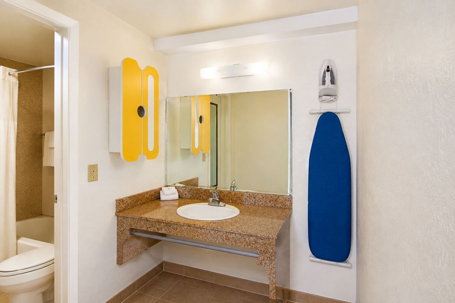 A bathroom with a sink, mirror, towel rack, and shower area.