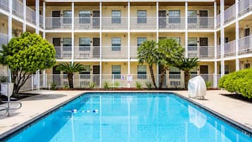 A multi-story hotel with a swimming pool, balconies, and tropical landscaping.