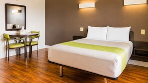 Une chambre d’hôtel comprenant un lit, des tables de chevet, un bureau avec des chaises et un miroir.