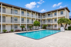 A multi-story hotel with a swimming pool, outdoor seating, and a covered area. - Studio 6 San Antonio, TX - Lackland AFB (San Antonio)