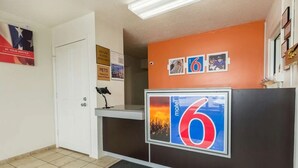 A reception desk with a large number '6' sign, a pet-friendly notice, and a 'pets' sign. - Motel 6 Troy, OH (Troy)
