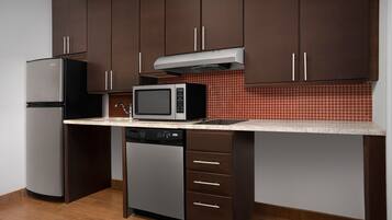 Una cocina con armarios de color marrón oscuro, un refrigerador de acero inoxidable, un microondas y un lavavajillas.