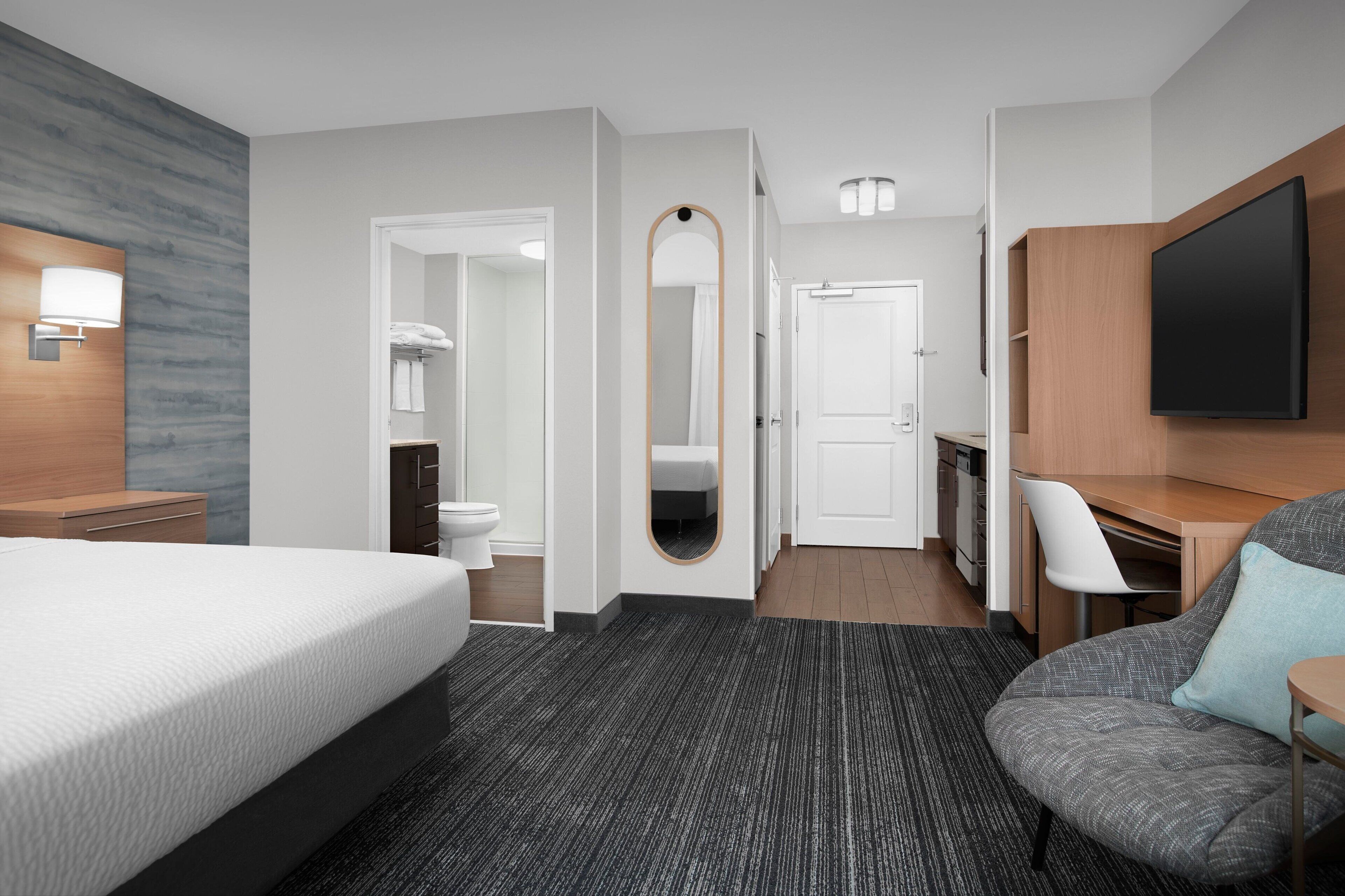 Une chambre d’hôtel moderne équipée d’un grand lit, d’un bureau, d’une télévision et d’une salle de bain.