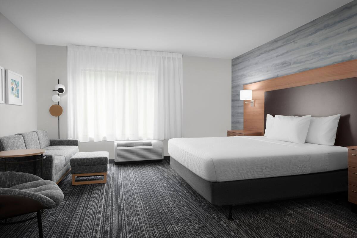 Une chambre d’hôtel moderne avec un grand lit, un canapé, une petite table et une chaise.