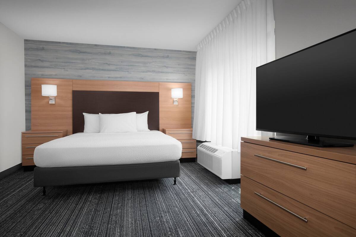 Une chambre d’hôtel équipée d’un lit, d’une télévision, d’une commode et d’un radiateur.