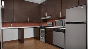 A modern kitchen with dark brown cabinets, a stainless steel refrigerator, a microwave, an oven, and a dishwasher.