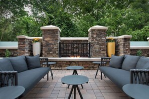 An outdoor patio area with stone walls, a built-in fire feature, and seating arrangements.