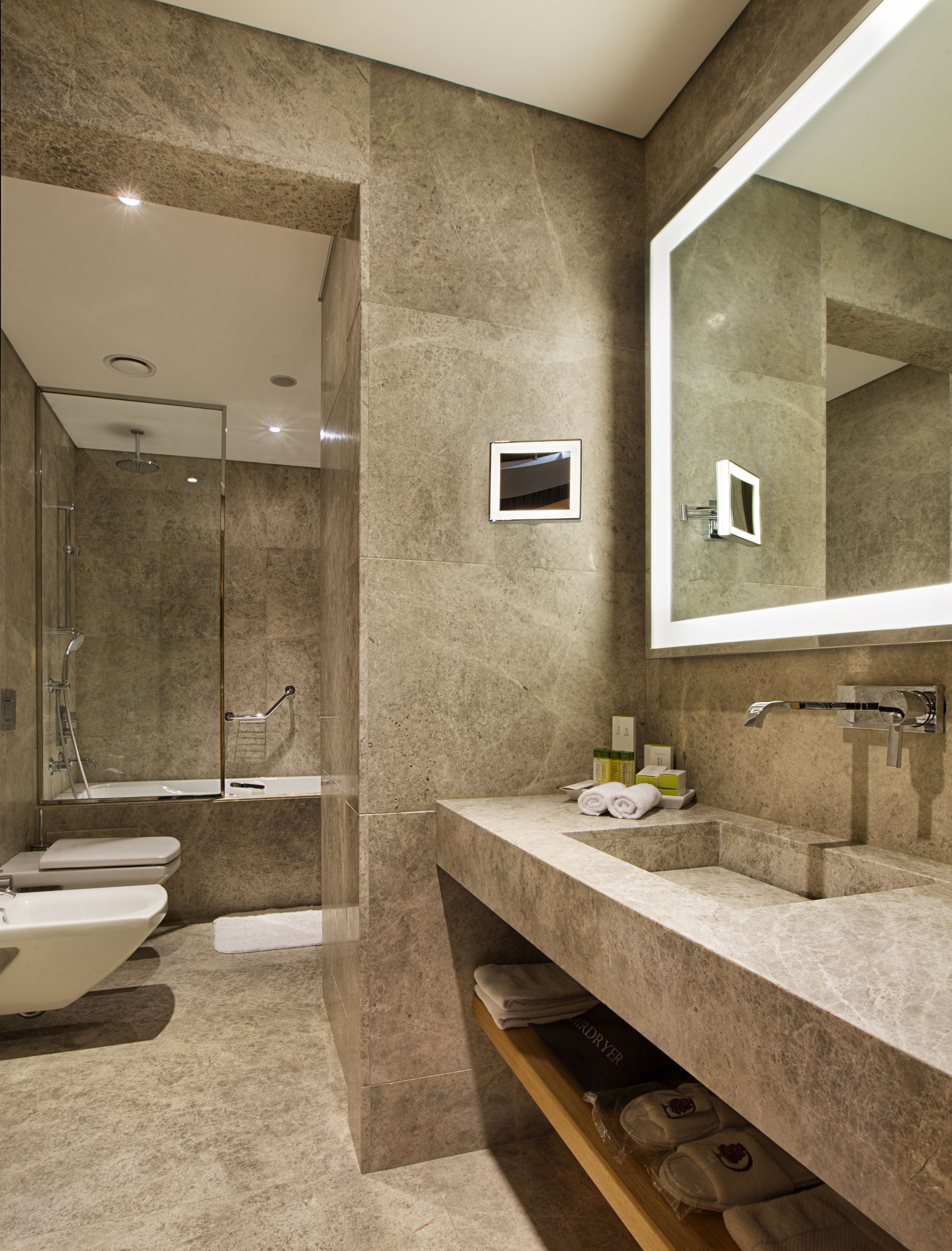 A modern bathroom with a large mirror, a shower, and a vanity with a sink and towel rack.