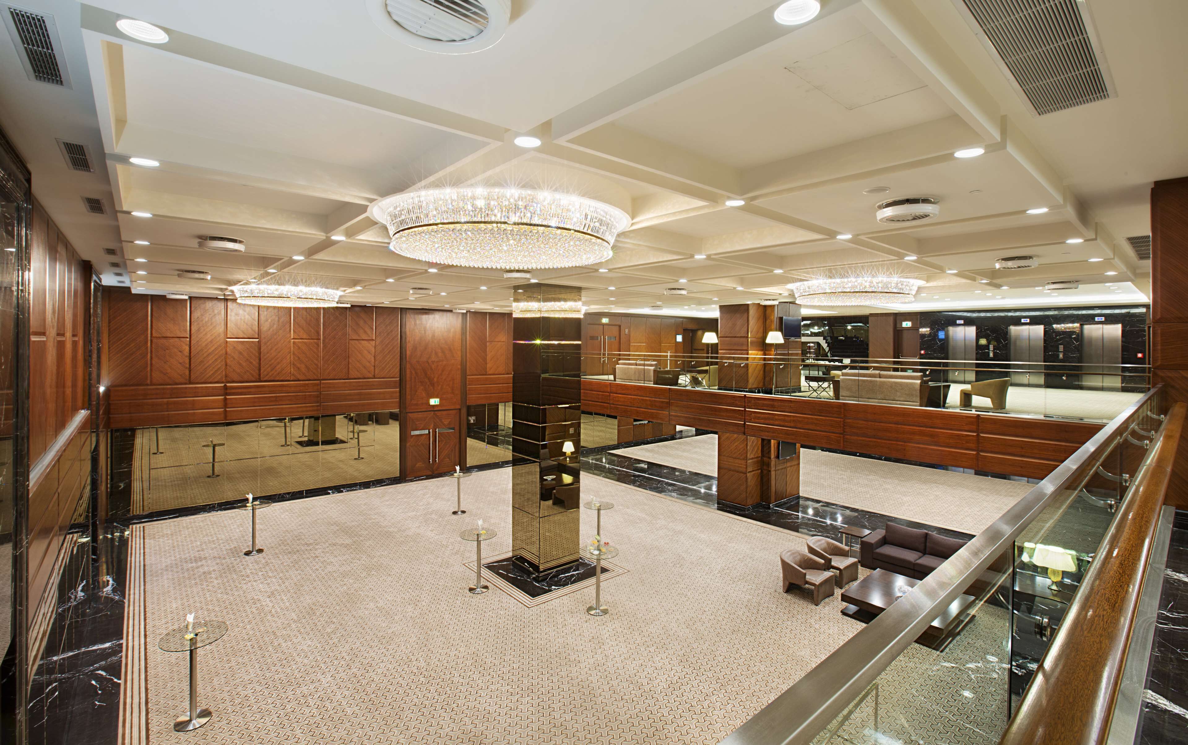 A spacious lobby with high ceilings, chandeliers, and a central column.