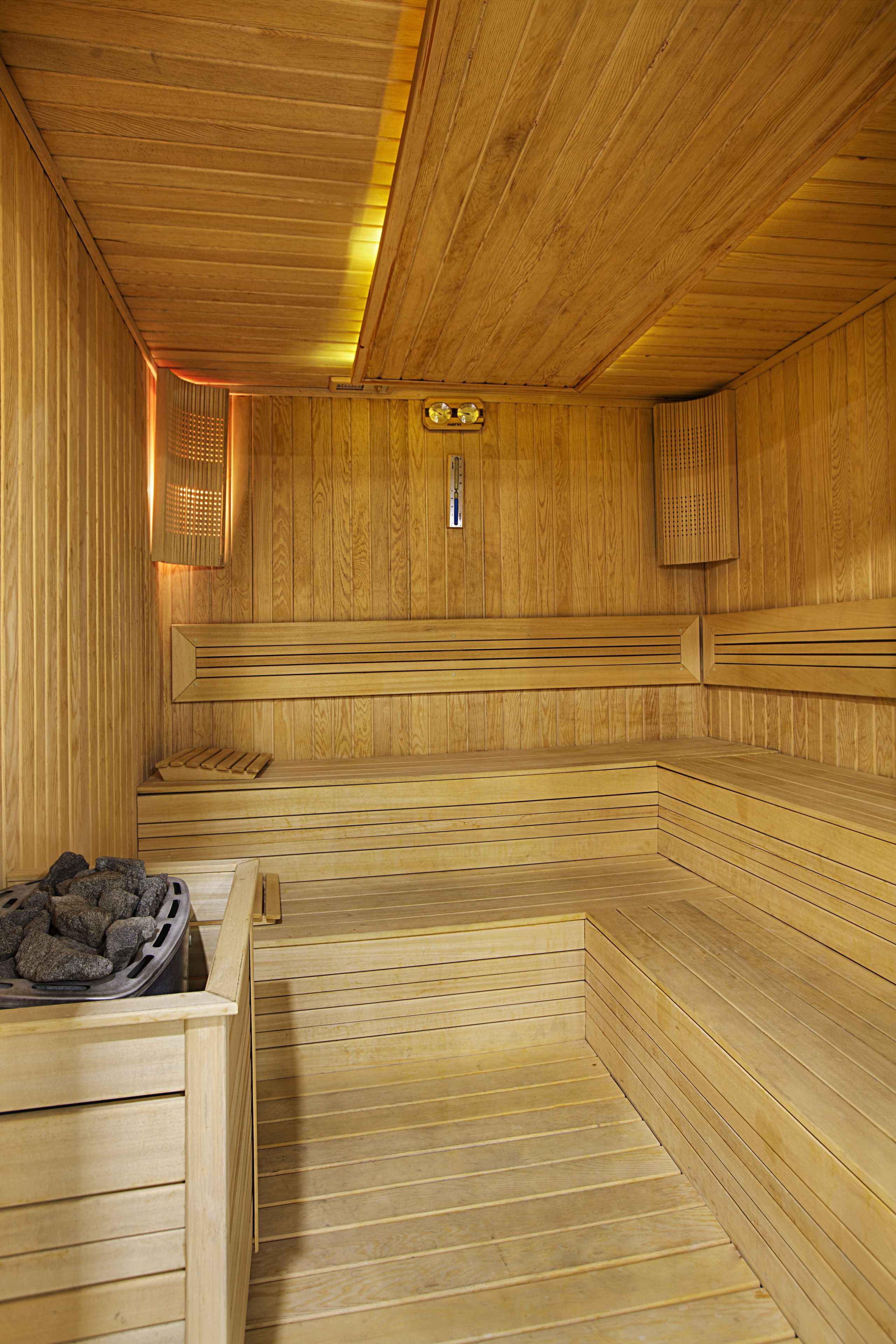 A wooden sauna with benches and a bench with a heating element.