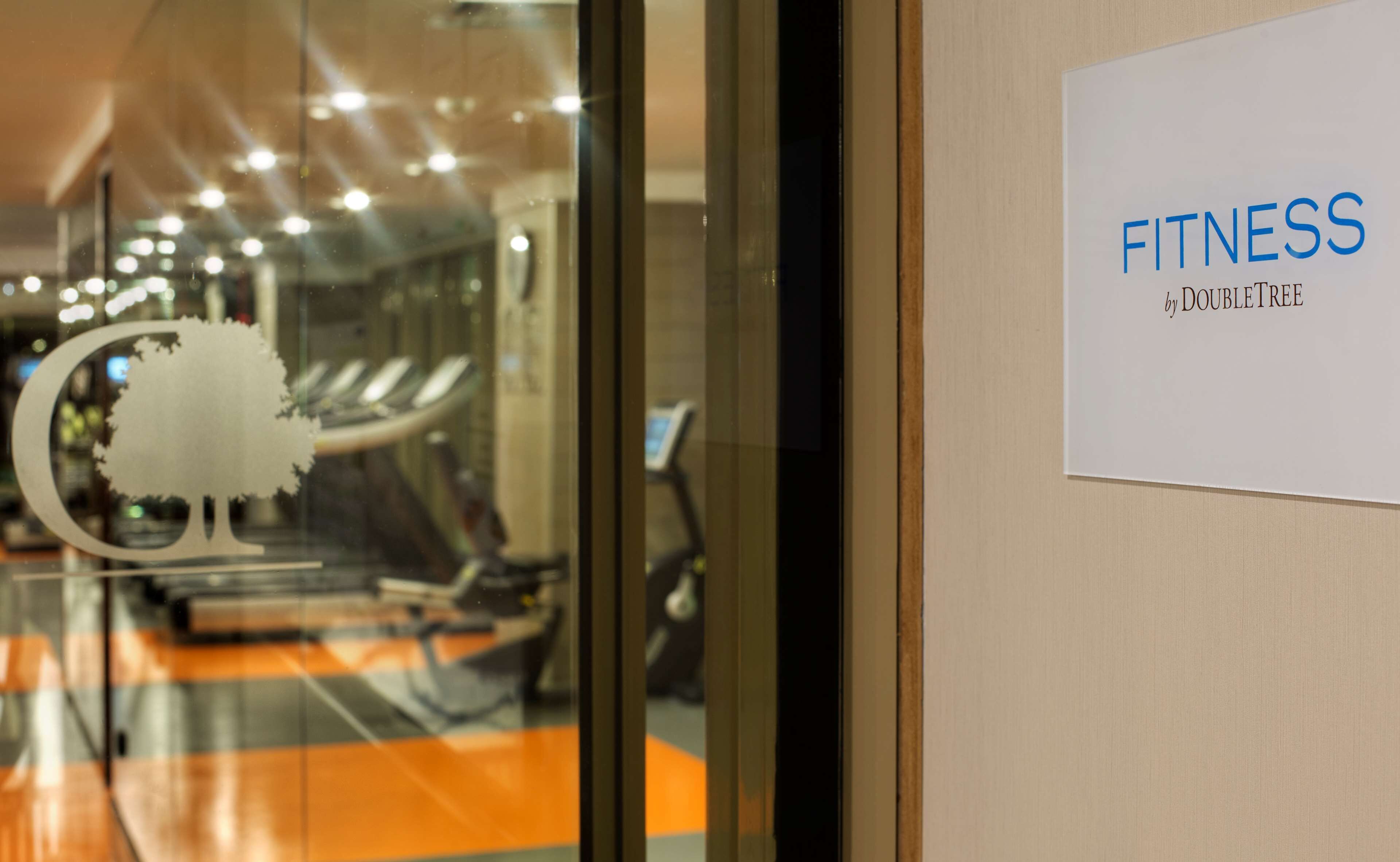 Interieur van een fitnessruimte met trainingsapparatuur en een bord met de locatie.