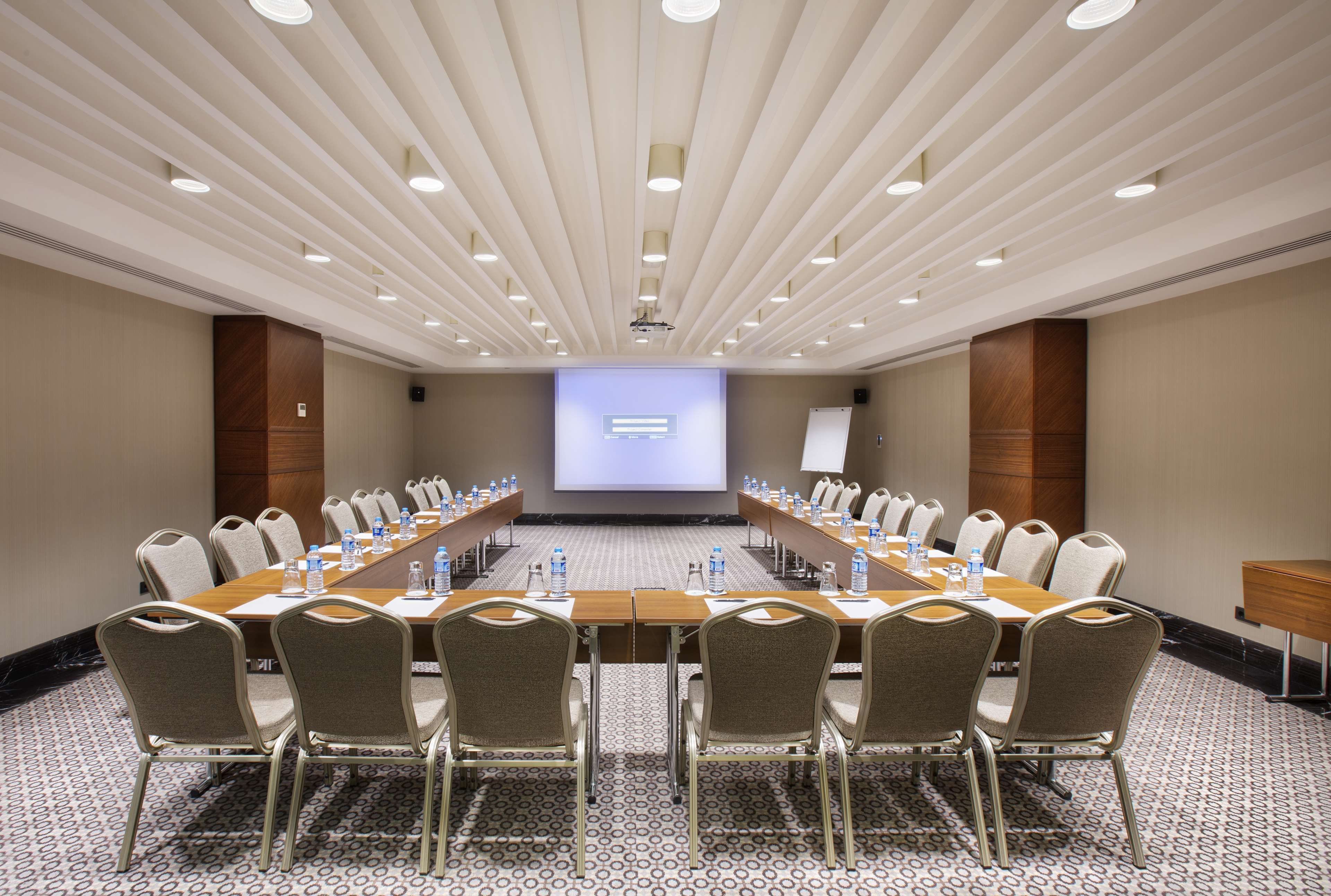A conference room with a long table, chairs, a projector screen, and a whiteboard.