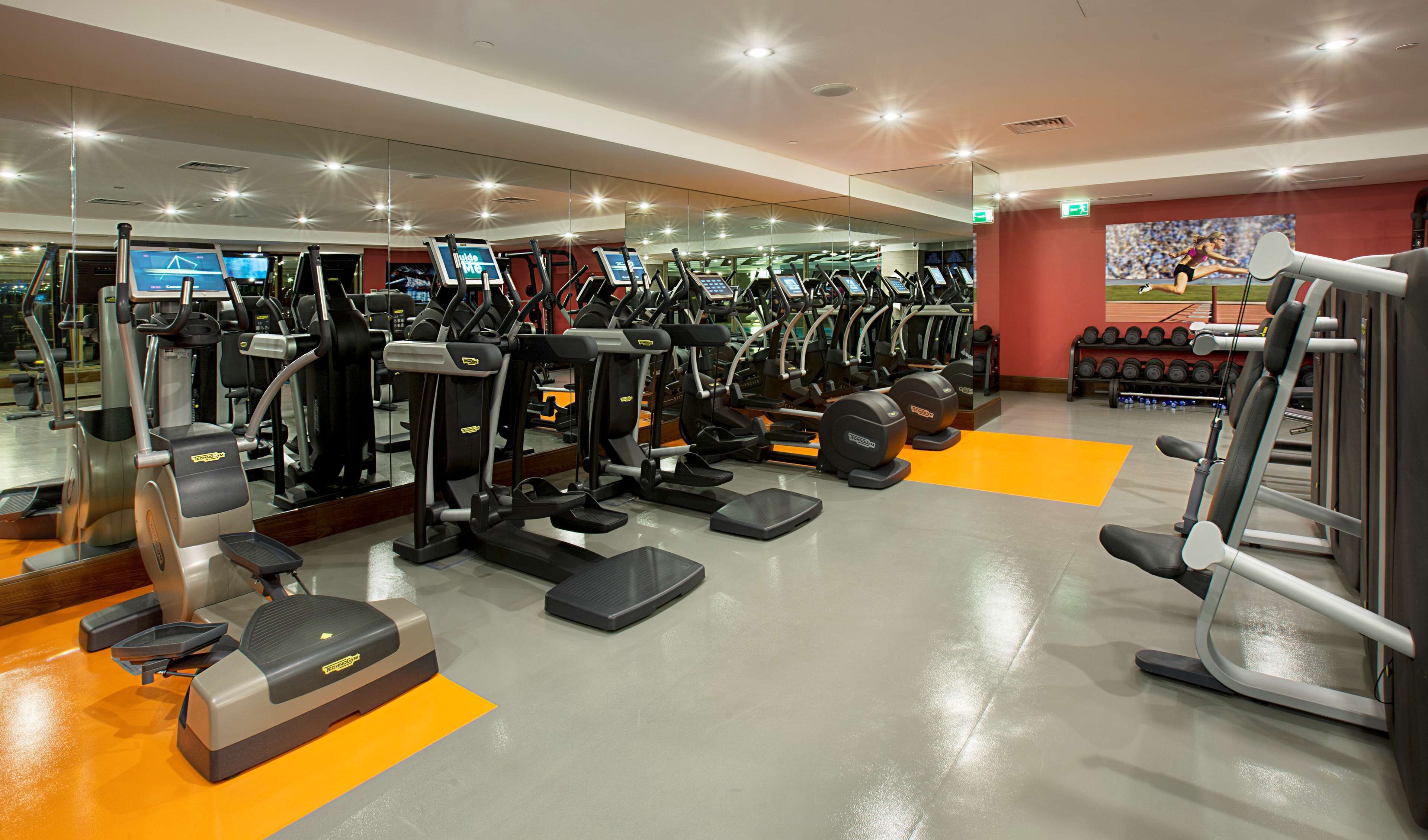 A gym with various exercise machines, mirrors, and a motivational poster on the wall.