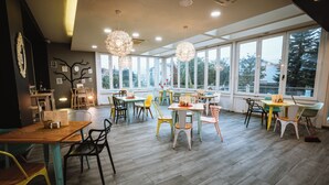 A spacious dining area with multiple tables and chairs, large windows, and a modern ceiling design. - La Sinagoga Hotel Spa (Hervas)