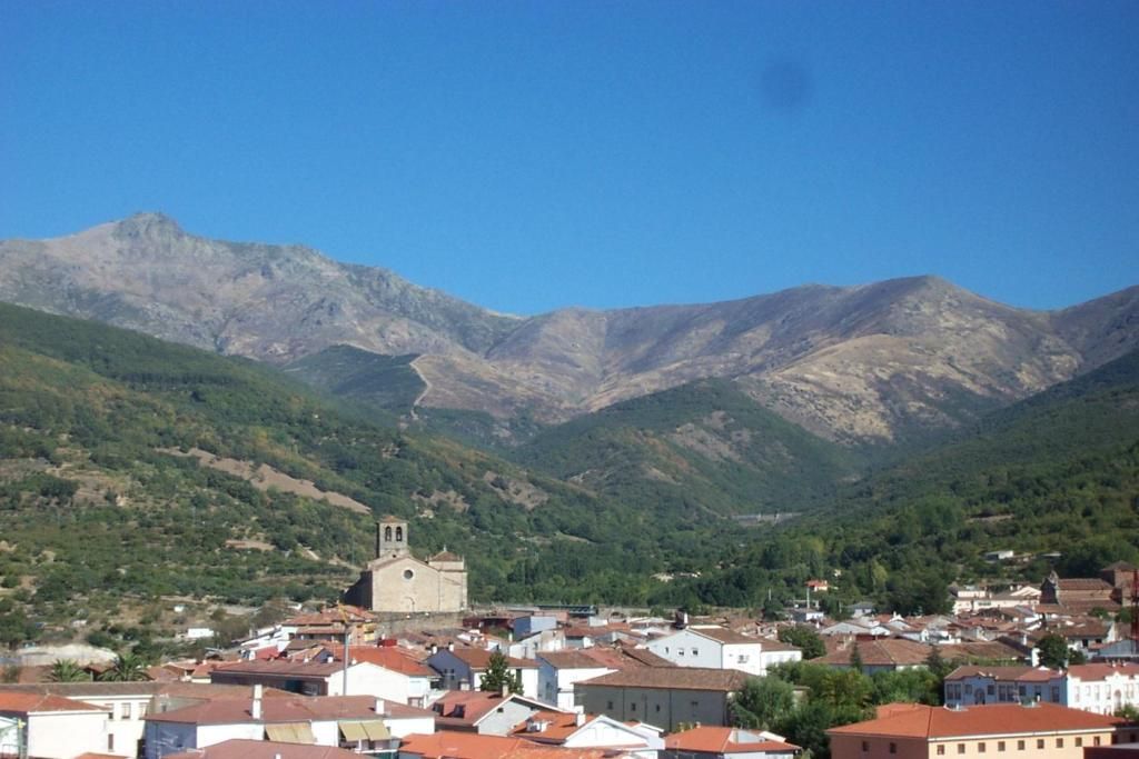 A town with a prominent church in the center, surrounded by residential buildings and mountains in the background.