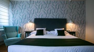 Habitación de hotel con una cama grande, dos mesitas de noche, una silla y un papel tapiz estampado.