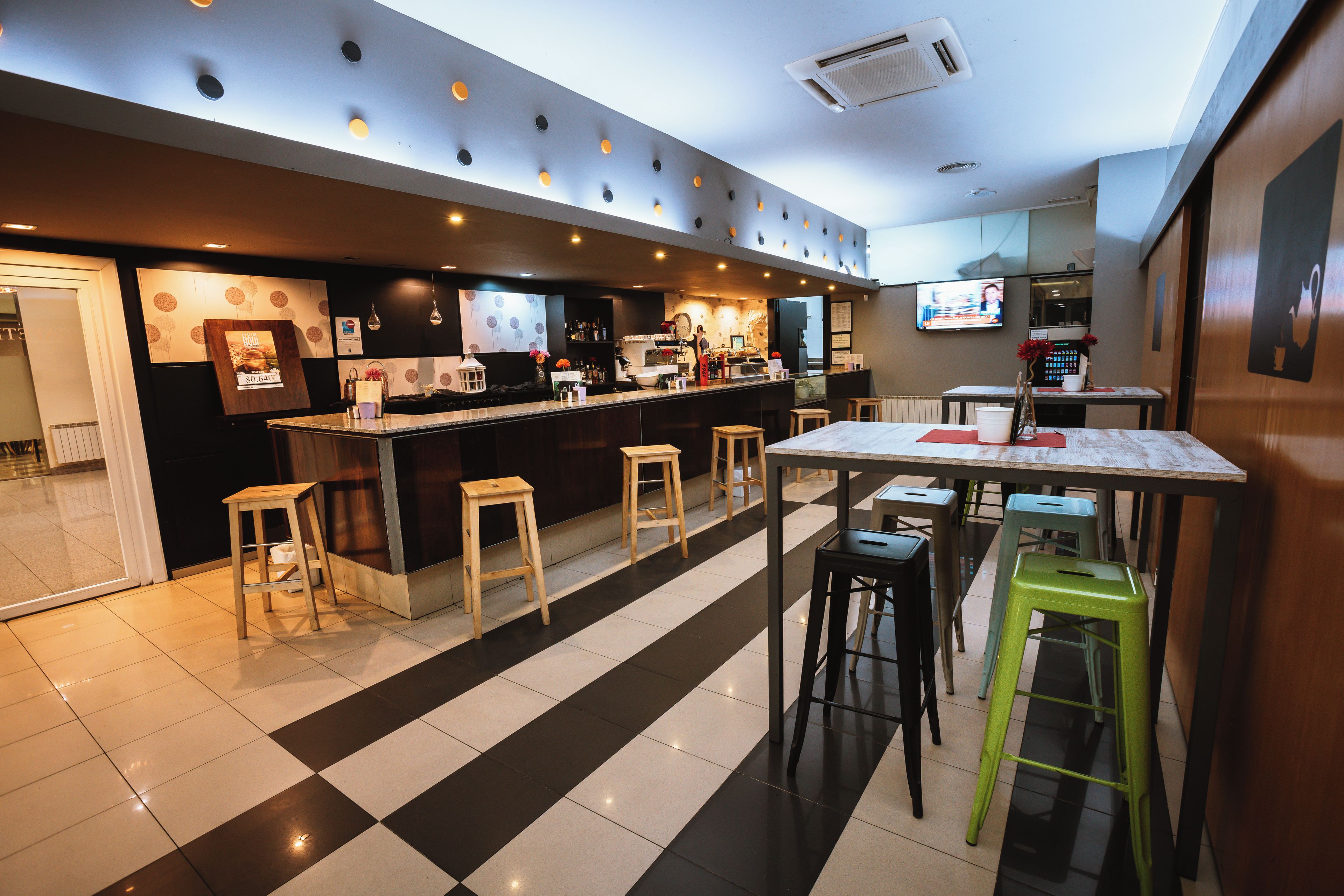 Une cuisine moderne avec un coin bar, des tabourets et un téléviseur.