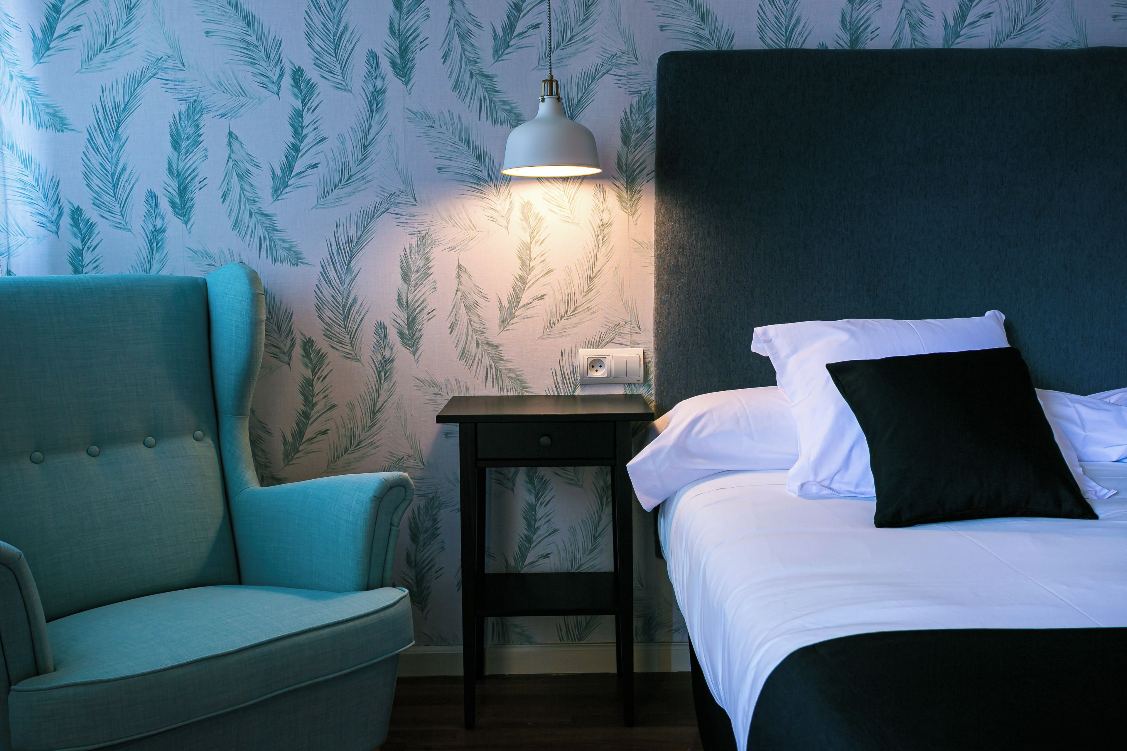 A room with a bed, a nightstand, a lamp, and a chair.