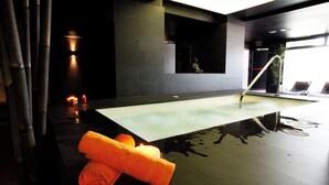 A spa area with a hot tub, towels, candles, and a view of the outside. - La Sinagoga Hotel Spa (Hervas)