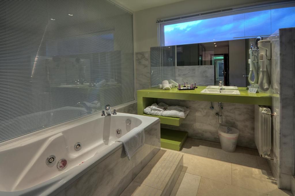A modern bathroom with a large bathtub, a vanity with a mirror, and a shower area.