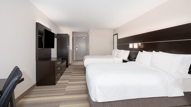 Habitación de hotel con dos camas, un escritorio, un televisor y un armario.