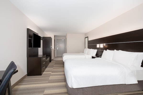 A hotel room with two beds, a desk, a TV, and a wardrobe.
