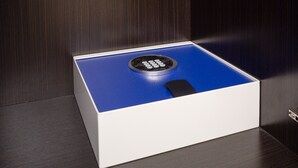 Una caja fuerte azul y blanca con teclado sobre una superficie de madera.
